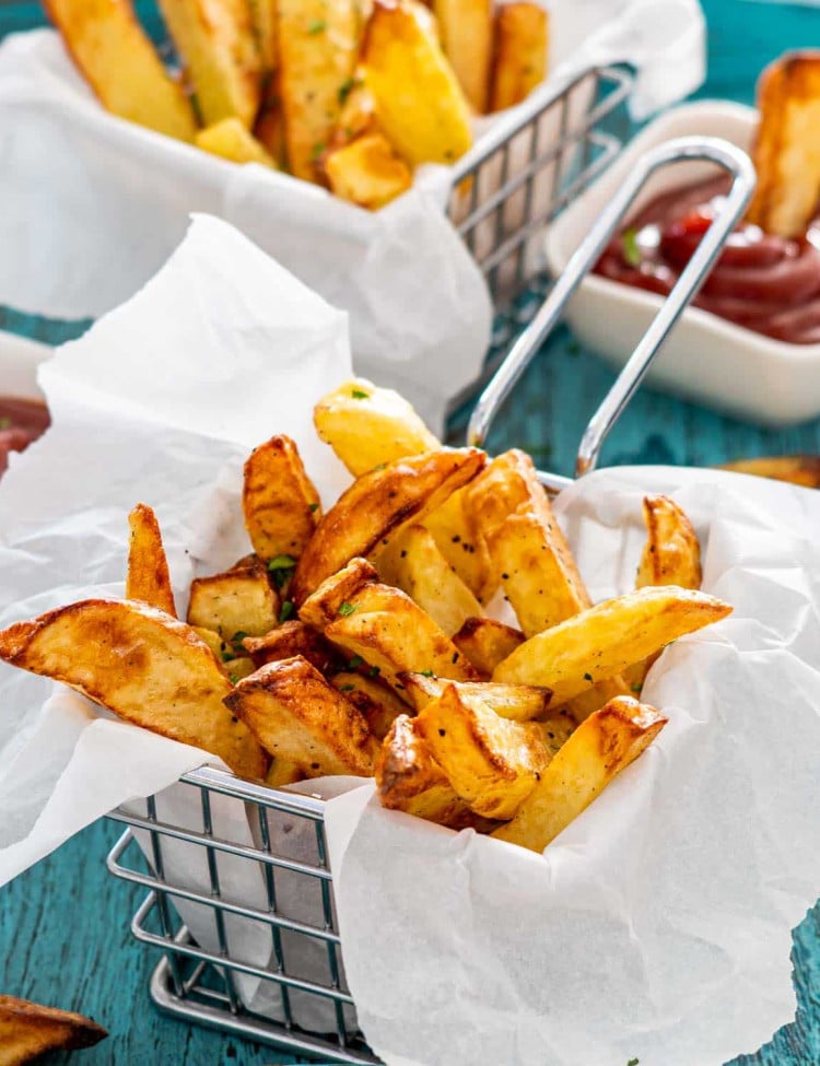french fries in a basket with a small bowl with ketchup.