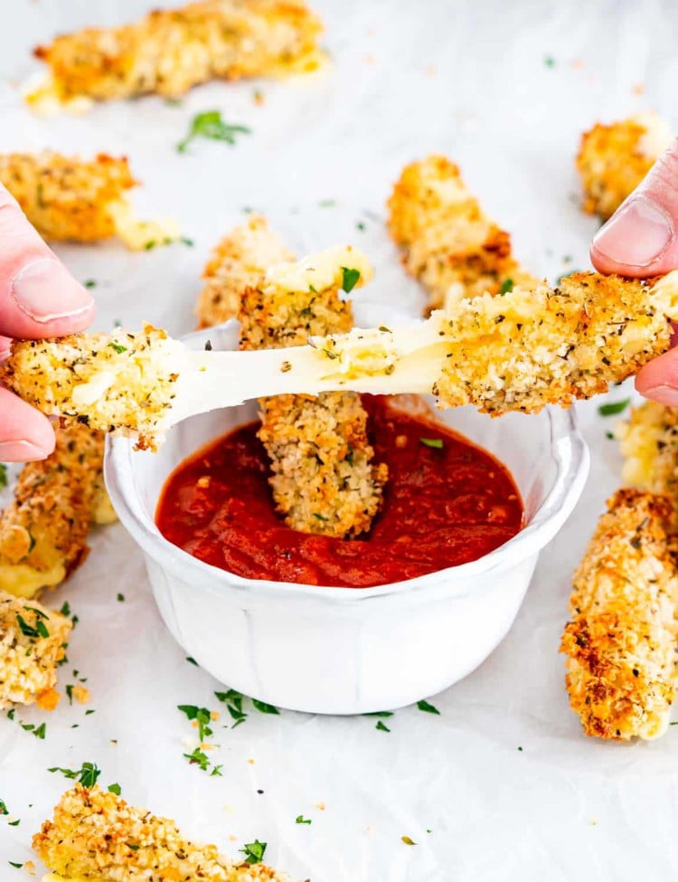 hands pulling apart a mozzarella stick with the rest in the background