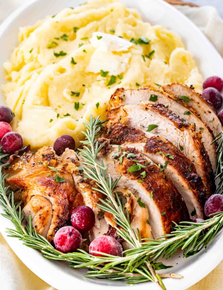 air fryer turkey breast on a white platter with mashed potatoes.