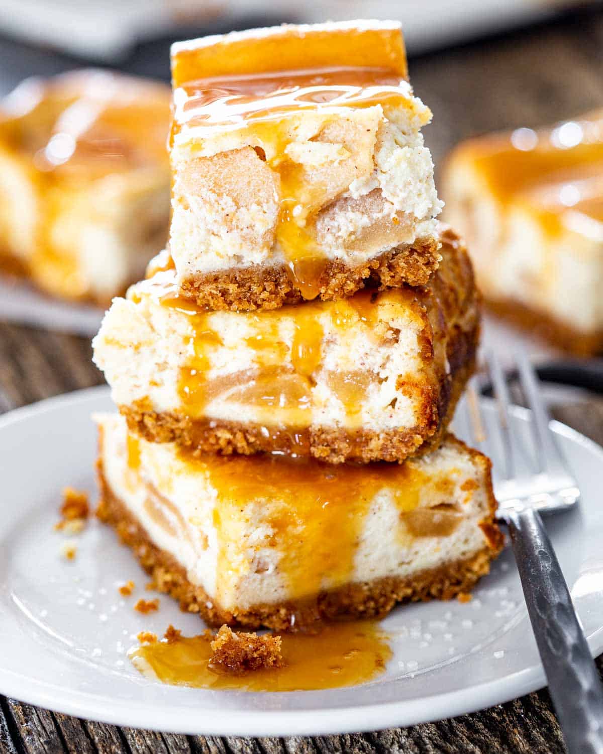 a stack of 3 apple pie cheesecake bars drizzled with salted caramel.