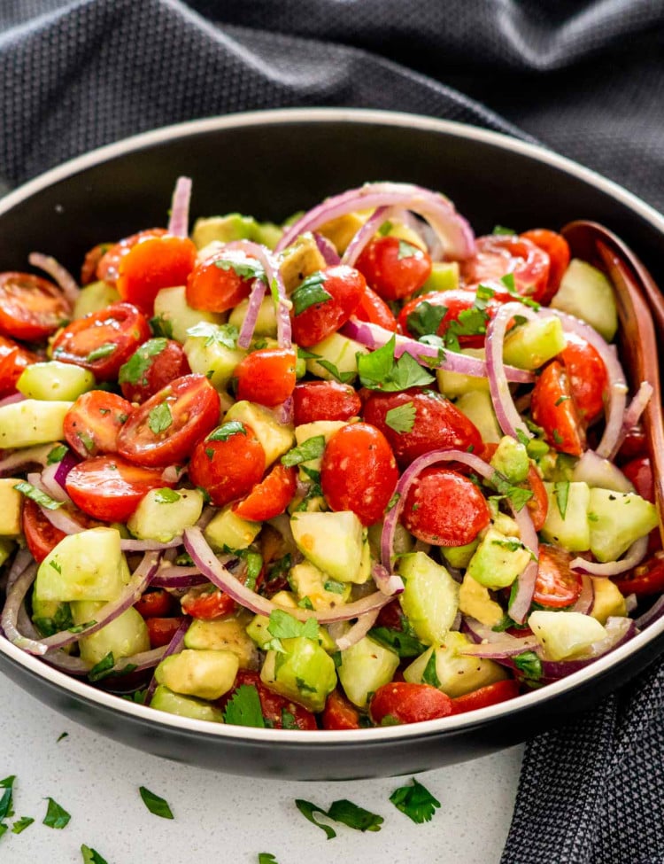 closeup of avocado salad in a black bowl.