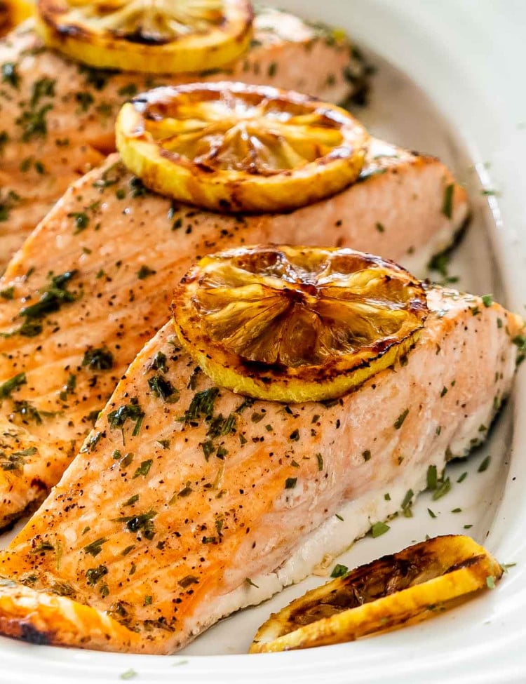 baked salmon with lemon slices on a white platter.