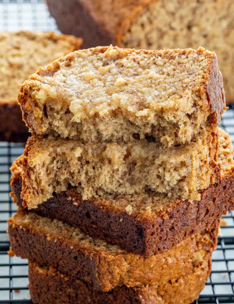 slices of banana bread stacked onto a black cooling rack.