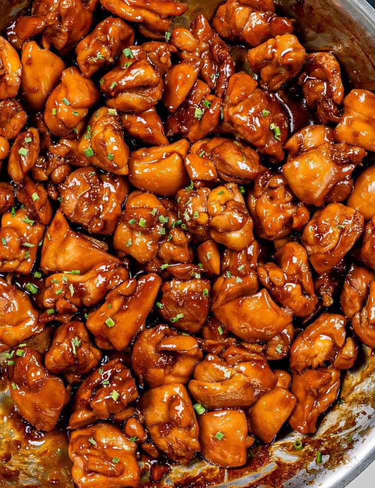 freshly made bourbon chicken in a skillet garnished with chives.