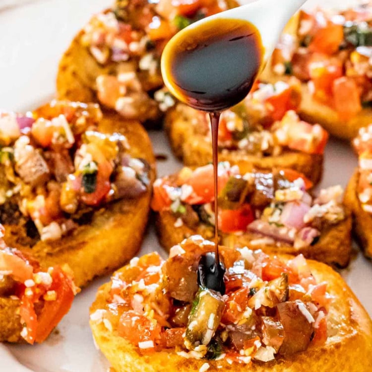 bruschetta on toasted baguette on a white platter.