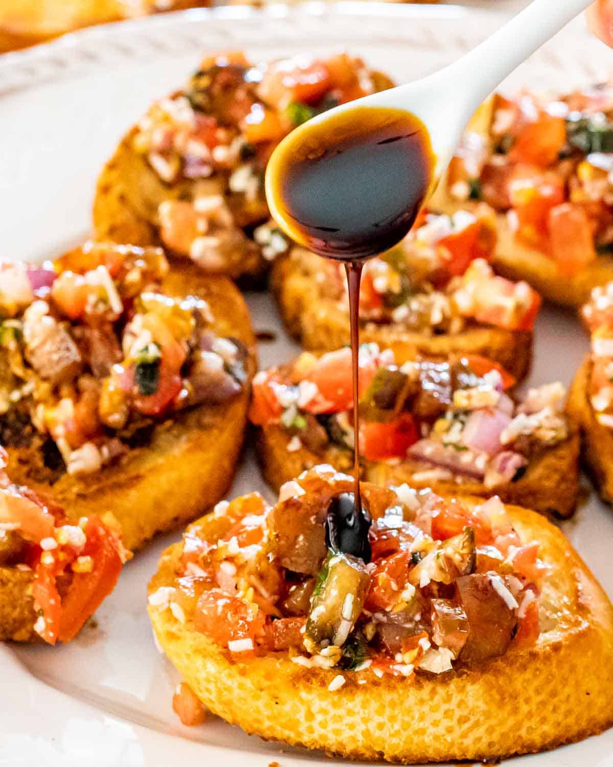bruschetta on toasted baguette on a white platter.