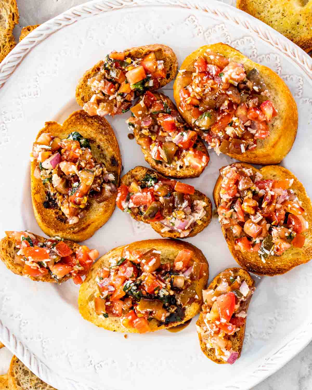 bruschetta on toasted baguette on a white platter.
