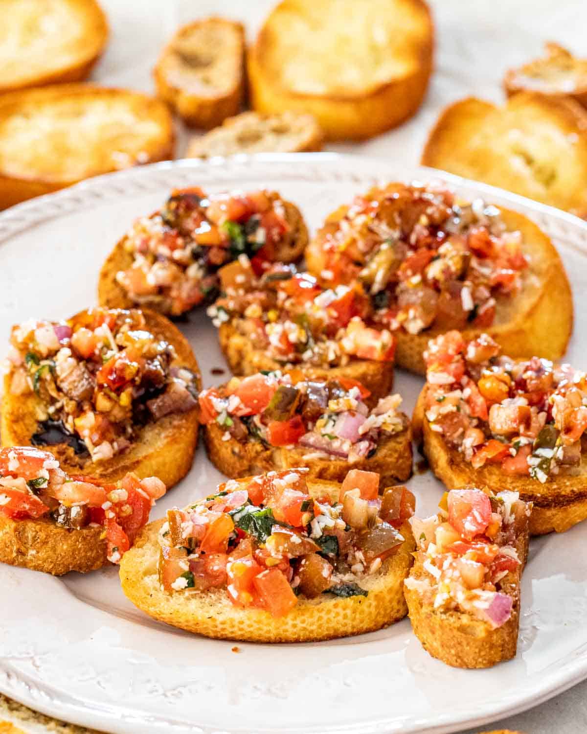 bruschetta on toasted baguette on a white platter.