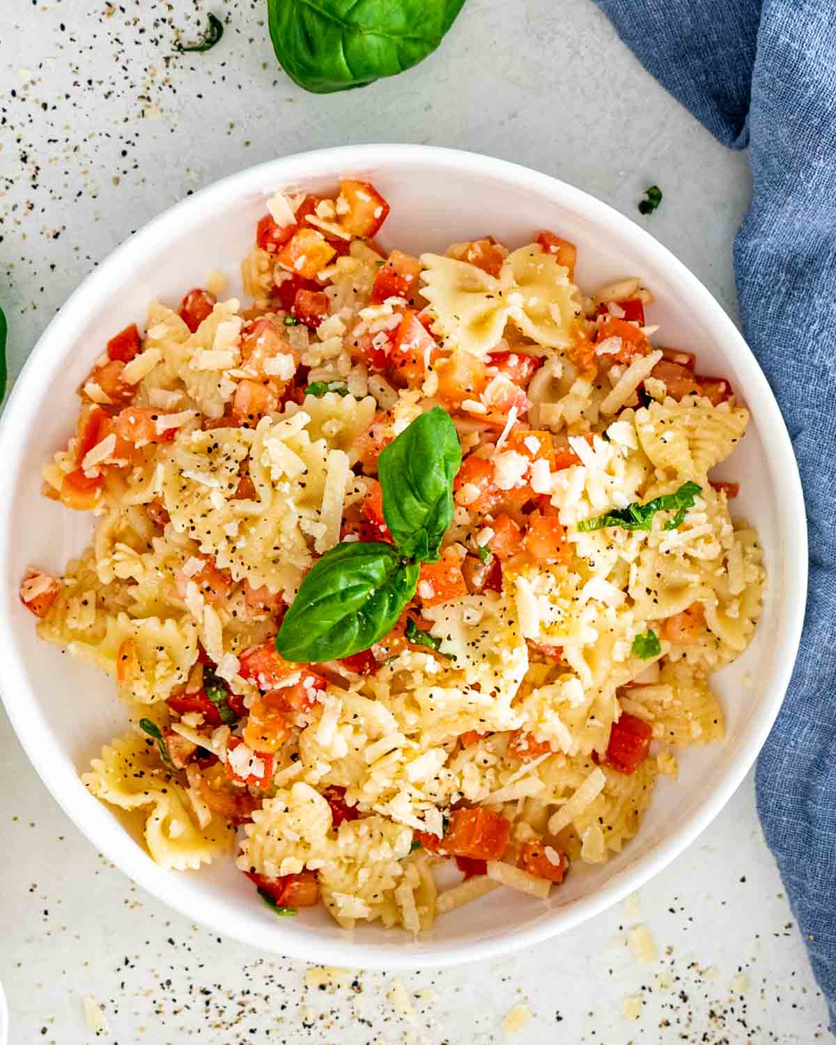 bruschetta pasta in a white bowl with a golden fork.