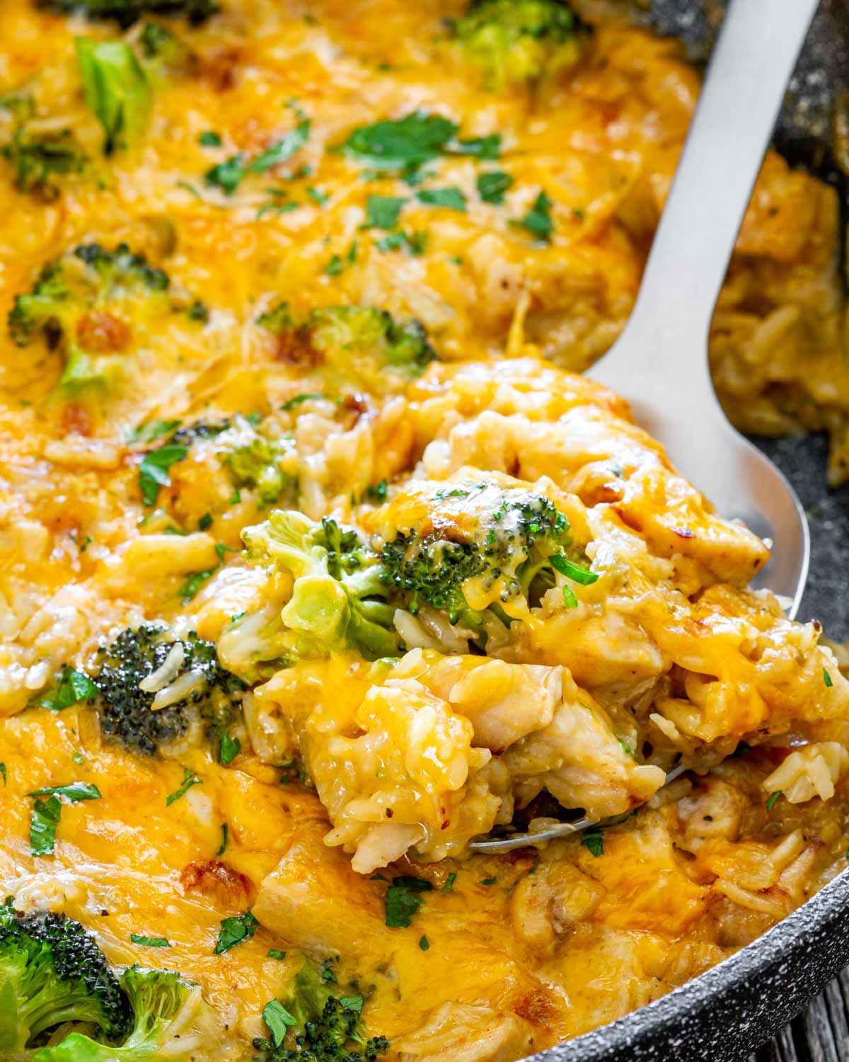 a serving spoon inside a skillet with chicken broccoli rice casserole.