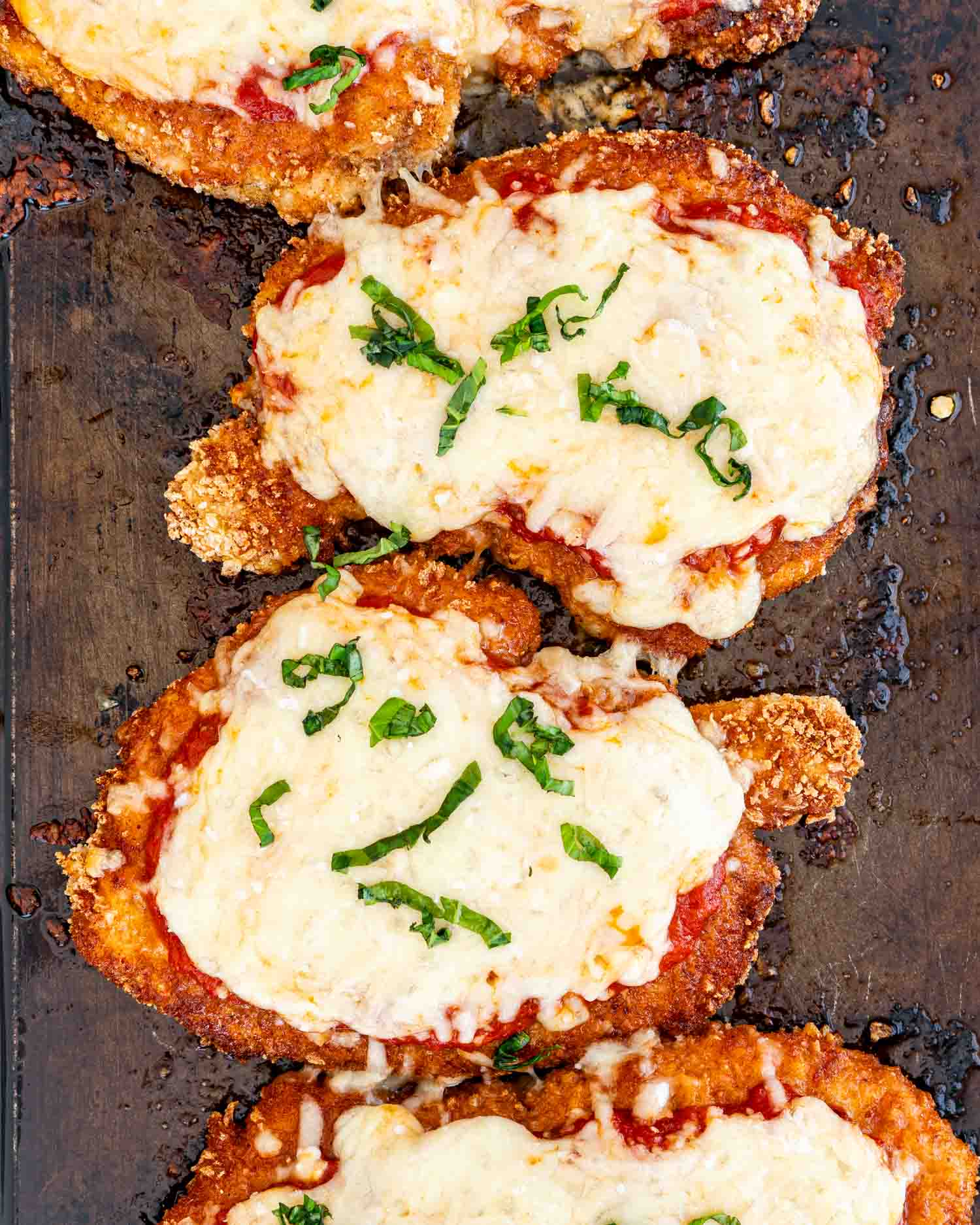chicken parmesan fresh out of the oven on a baking sheet.