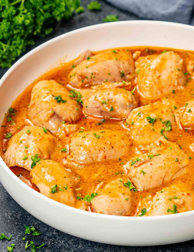crockpot thai chicken thighs with sauce in a white bowl.