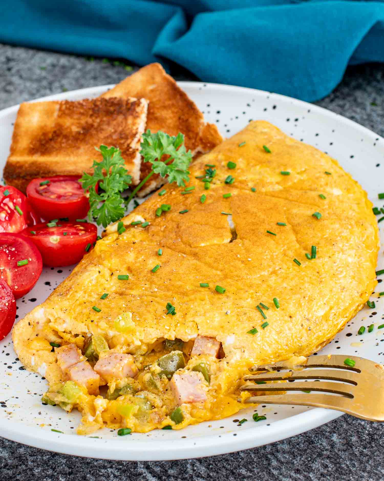 a denver omlette on a plate alongside some cherry tomatoes and toast.