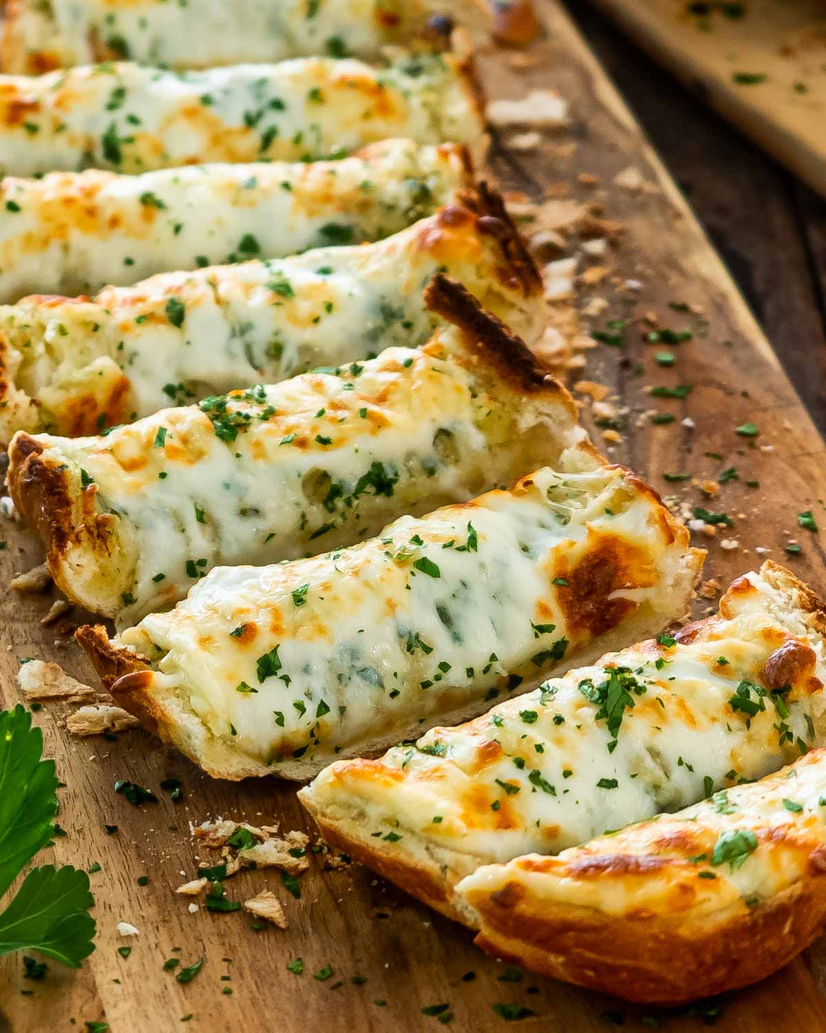 cheesy garlic bread fresh out of the oven sliced on a cutting board.