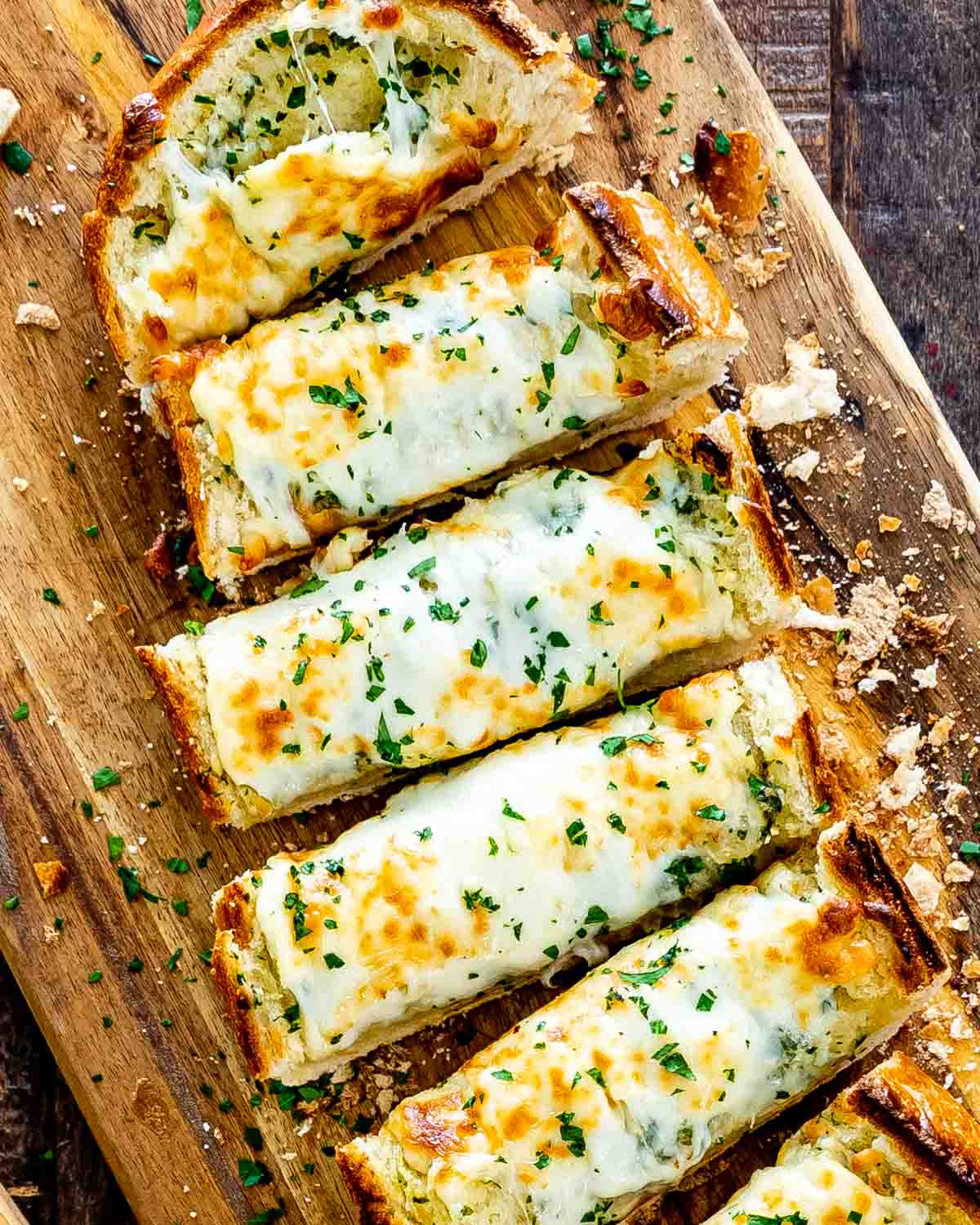 cheesy garlic bread fresh out of the oven sliced on a cutting board.