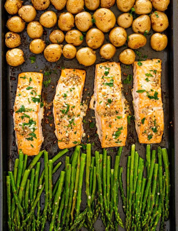garlic butter salmon with asparagus and baby potatoes on a sheet pan.