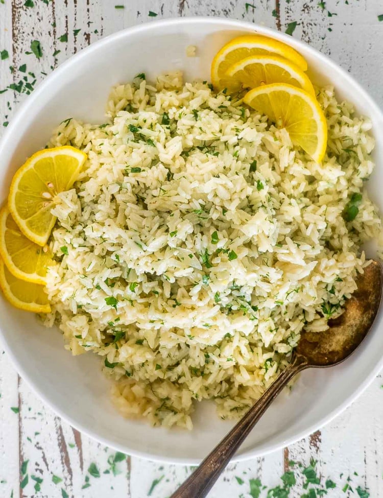 greek rice in a white bowl garnished with lemon slices.