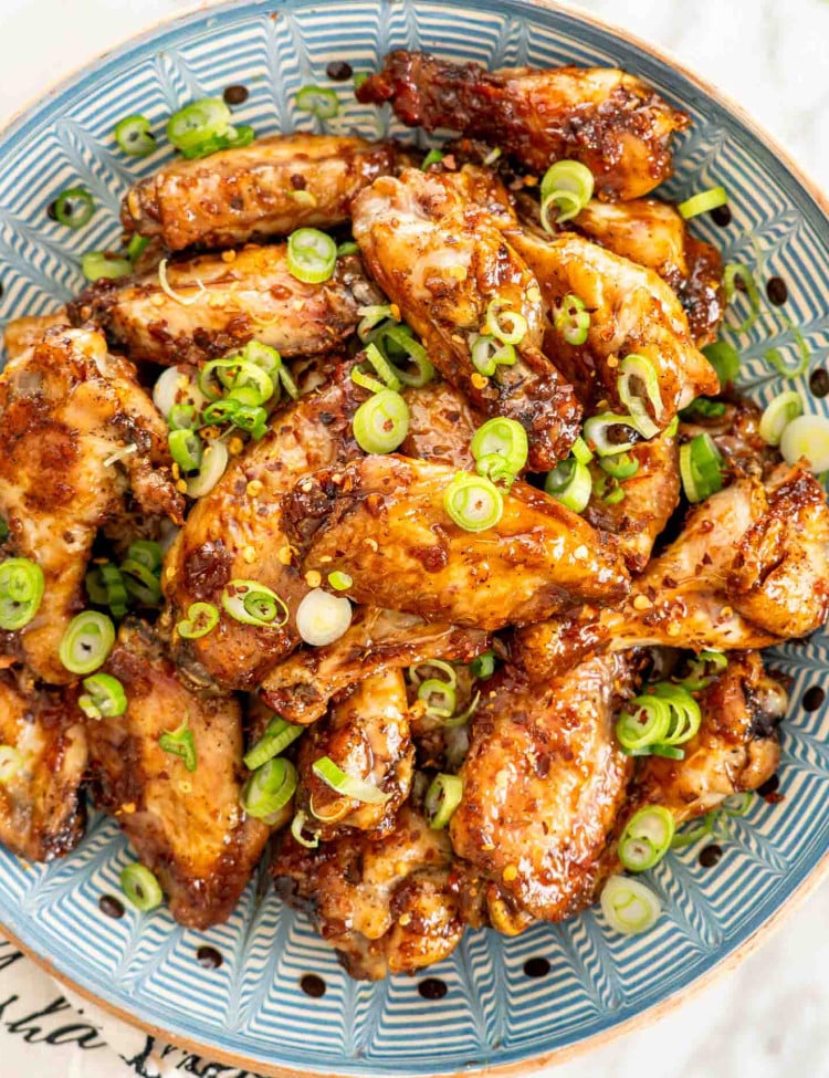 freshly made honey garlic chicken wings in a blue bowl.