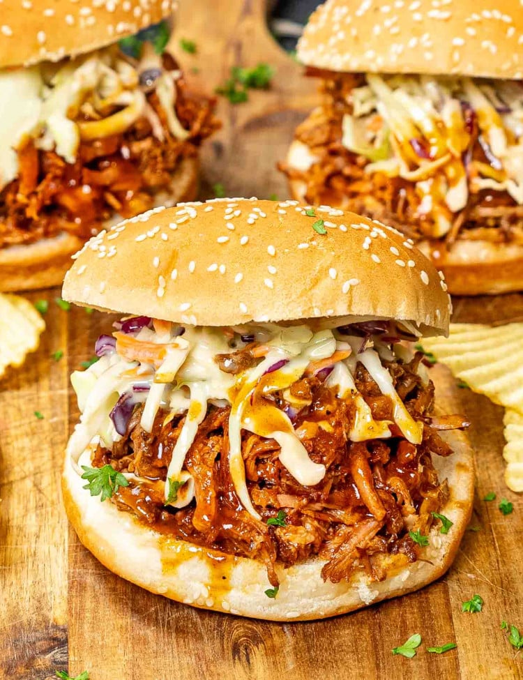 a pulled pork sandwich on a bun with lots of coleslaw and bbq sauce.