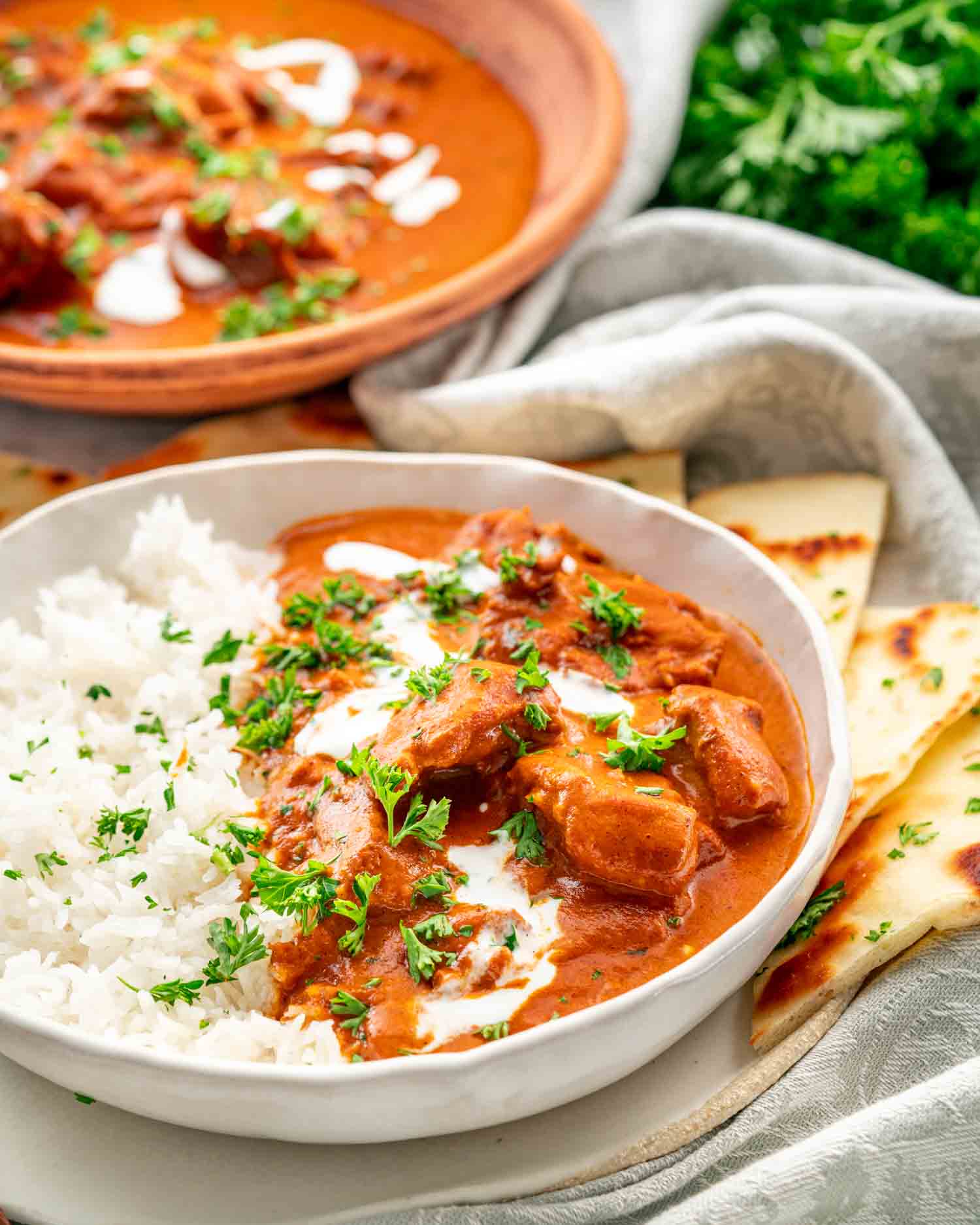 butter chicken over a bed of rice on a plate with naan.