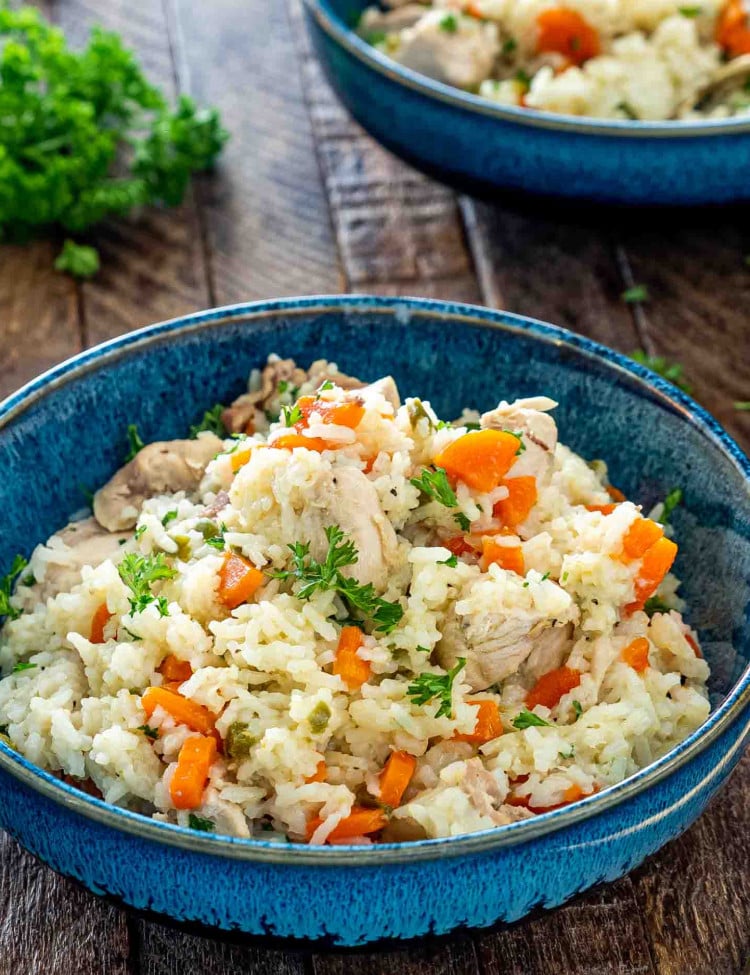 chicken and rice made in the instant pot in a blue bowl garnished with parsley.