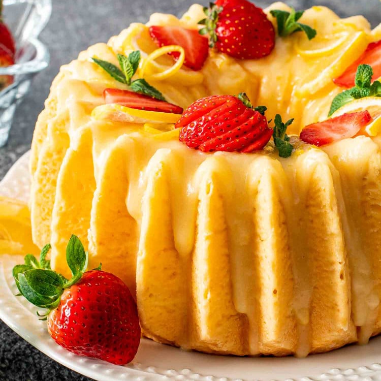 a lemon chiffon cake on a platter garnished with lemon slices and strawberries.