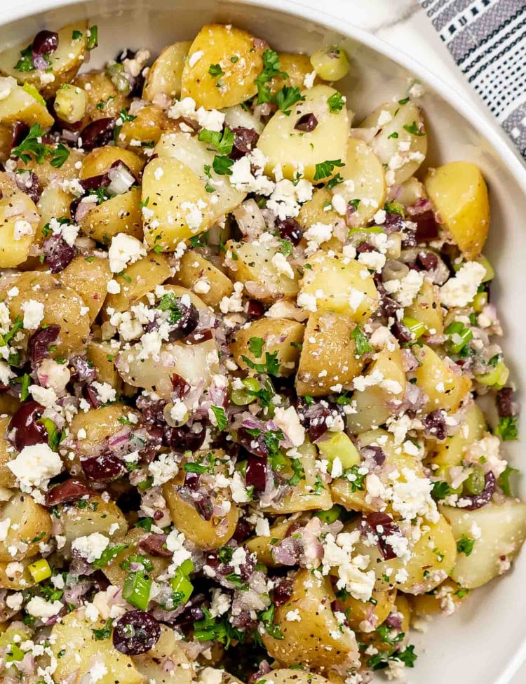 freshly made mediterranean potato salad in a white bowl.