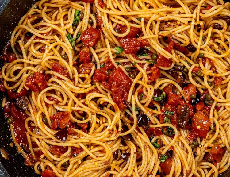 freshly made pasta puttanesca in a blue skillet.