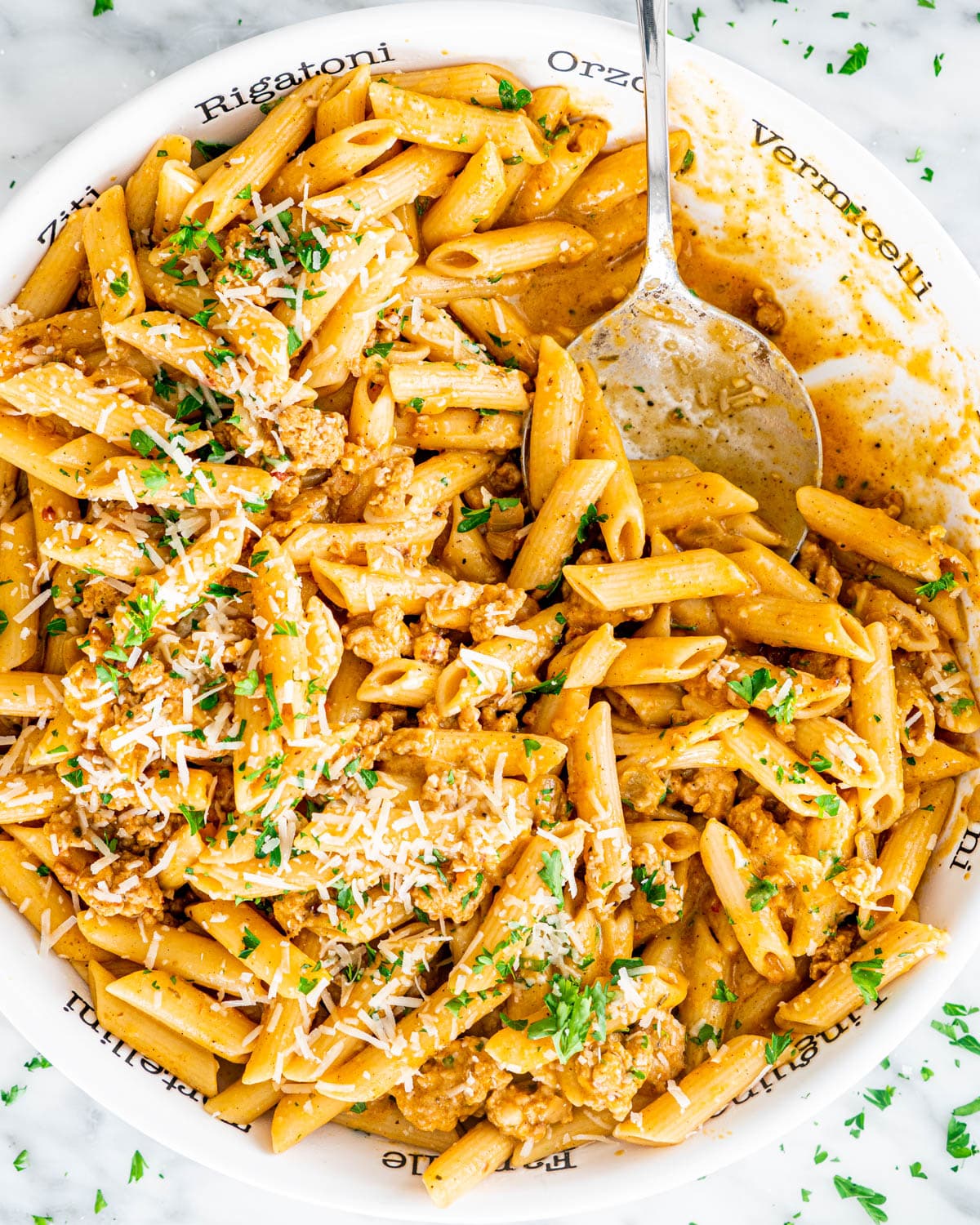 overhead shot of pumpkin sausage pasta in a pasta bowl with a serving spoon in it