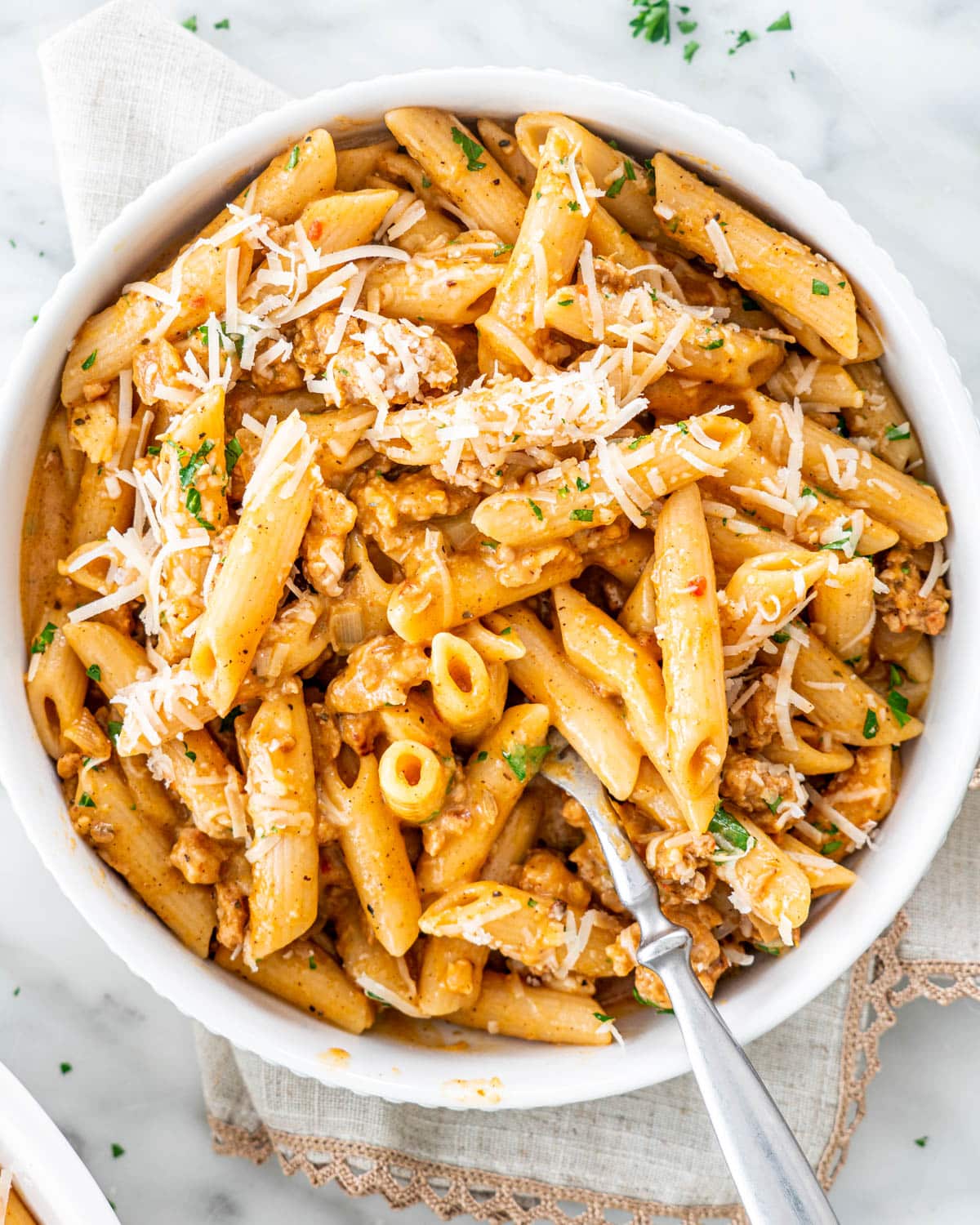 pumpkin sausage pasta in a white bowl with a fork in it