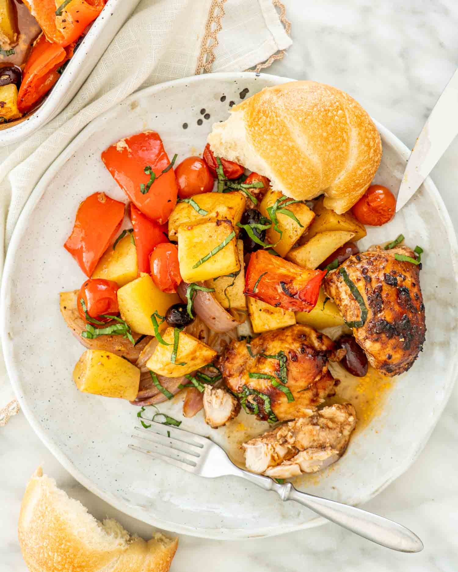 a white plate with roasted chicken and vegetables.