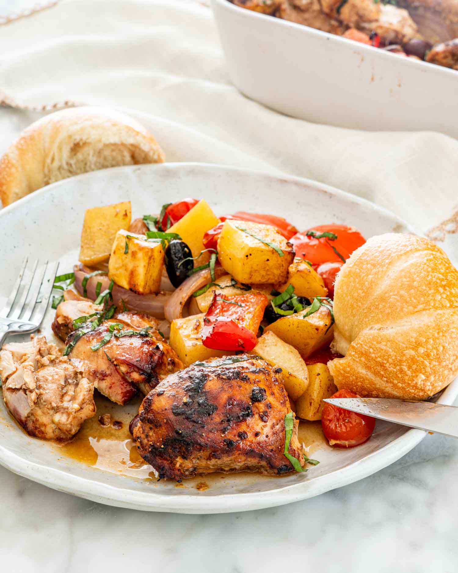 a white plate with roasted chicken and vegetables.