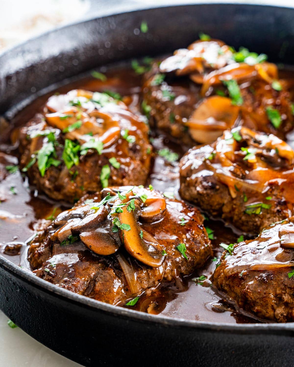 a skillet full of salisbury steak with mushroom gravy