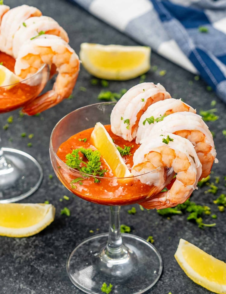 Cocktail glasses filled with shrimp cocktail, beautifully garnished with fresh lemon wedges and parsley on a table.