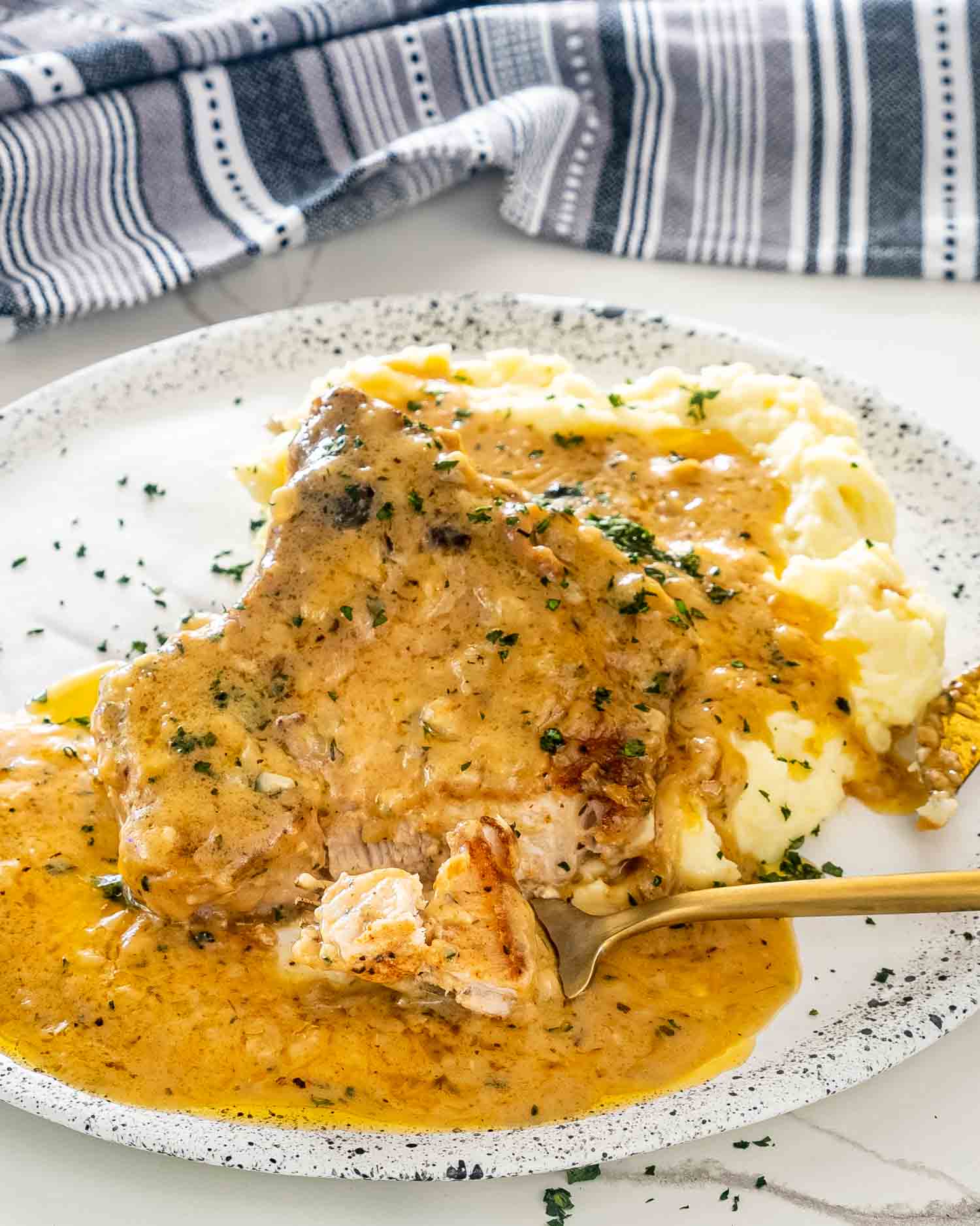 a smothered pork chop over a bed of mashed potatoes.