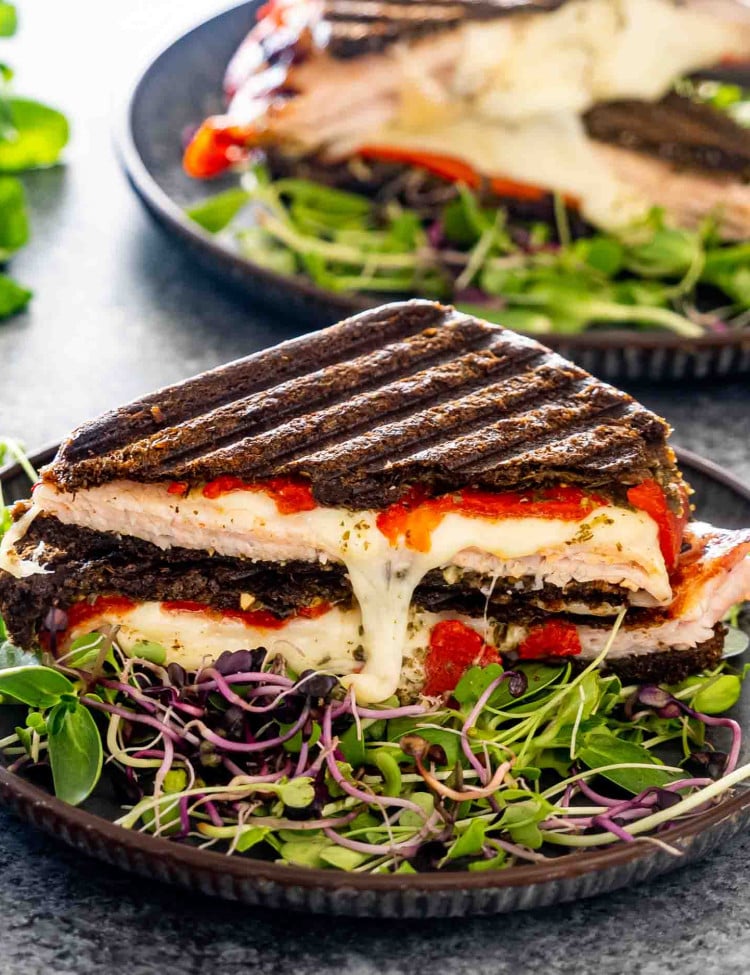 turkey panini with cheddar cheese and pesto on a metal plate.