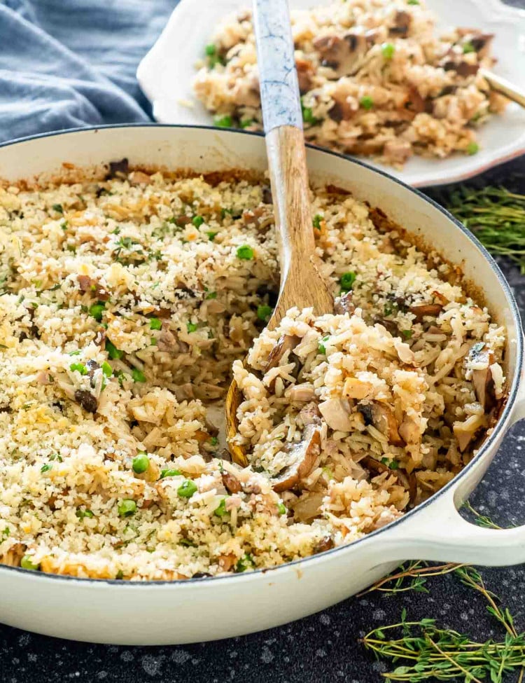 turkey rice casserole in a beige braiser with a spoon inside.