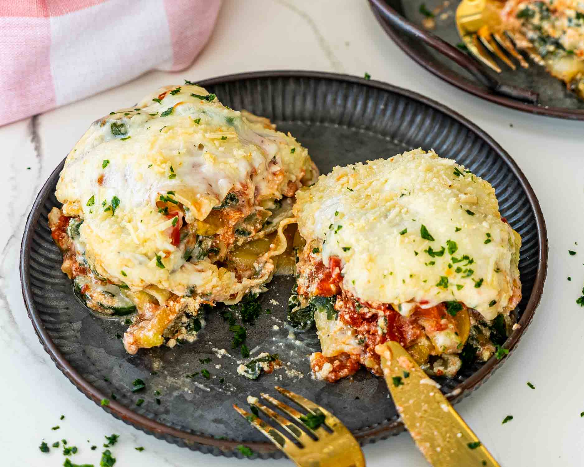 a slice of vegetable lasagna sliced in half on a plate.