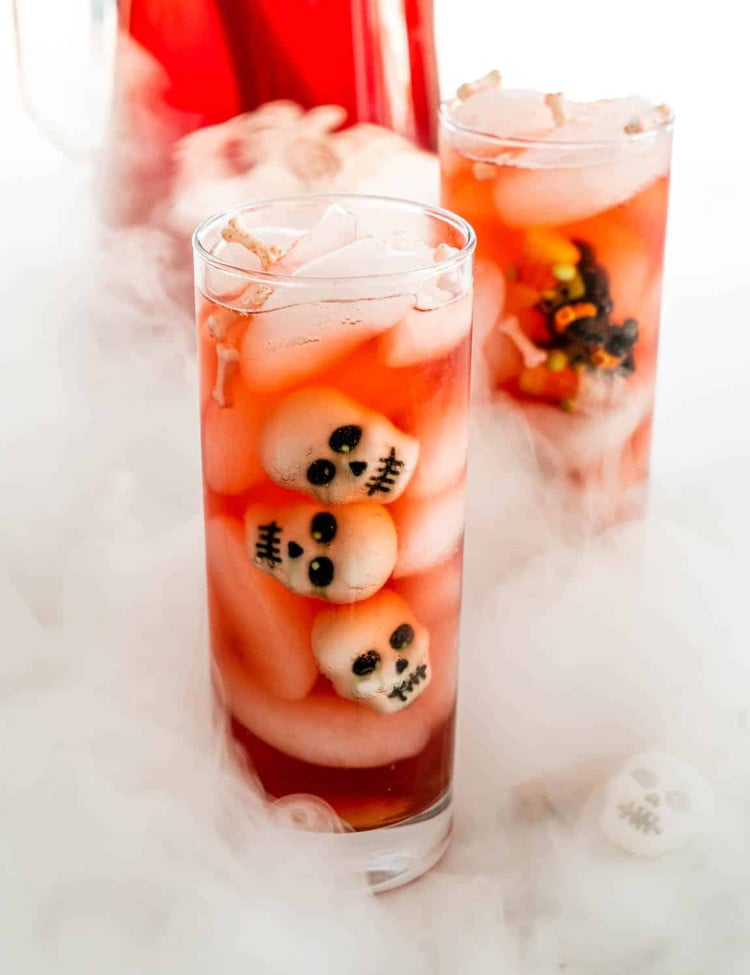side view shot of glasses of witches brew with decorative skulls floating in the drink. The glasses are surrounded by smoke